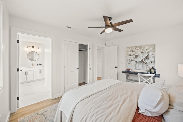 bedroom featuring ceiling fan, connected bathroom, a closet, and light wood-type flooring