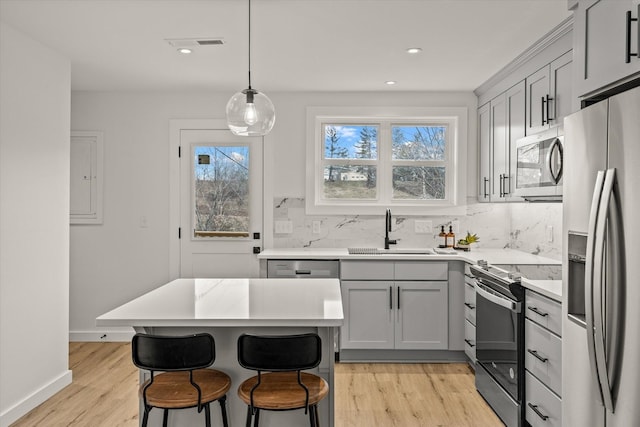 kitchen featuring decorative light fixtures, sink, gray cabinetry, decorative backsplash, and stainless steel appliances