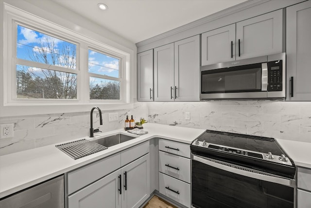 kitchen with electric stove, sink, tasteful backsplash, and gray cabinetry