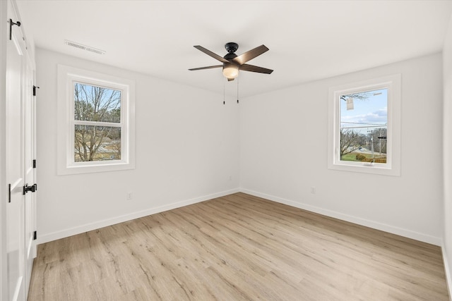 spare room with a wealth of natural light, ceiling fan, and light wood-type flooring