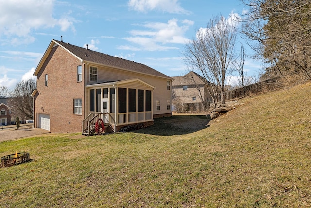 rear view of house with a garage, a sunroom, and a lawn