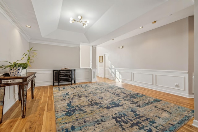 interior space with an inviting chandelier, a tray ceiling, light hardwood / wood-style floors, and crown molding