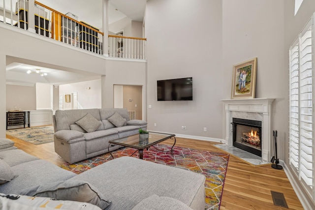 living room featuring a towering ceiling, a high end fireplace, and hardwood / wood-style floors