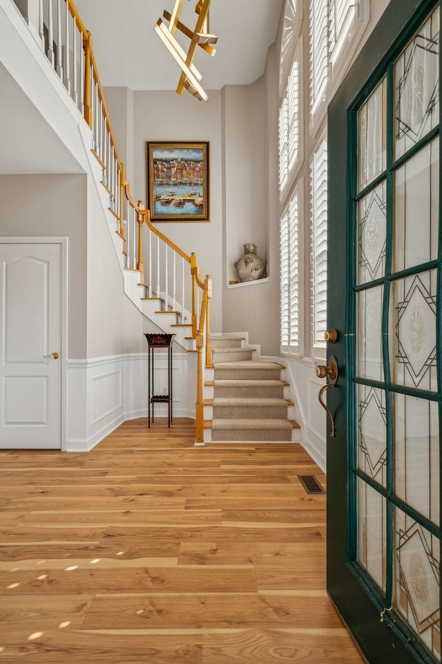 foyer with light hardwood / wood-style flooring, a healthy amount of sunlight, and a high ceiling