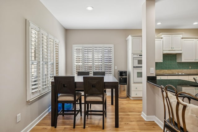 kitchen with white cabinetry, double oven, tasteful backsplash, and light hardwood / wood-style flooring