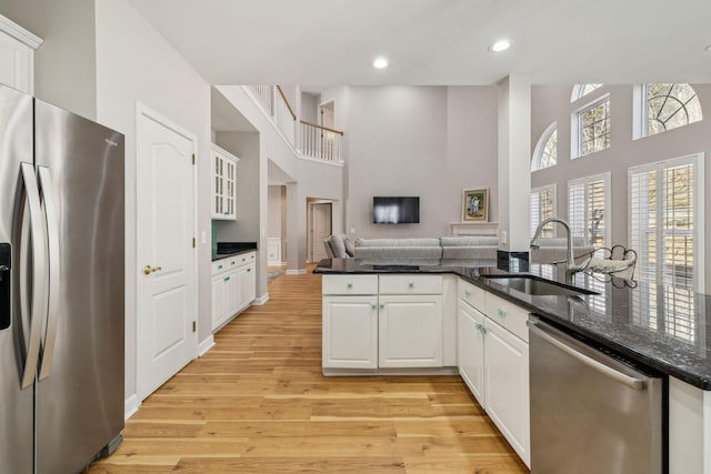 kitchen featuring appliances with stainless steel finishes, sink, white cabinets, kitchen peninsula, and light wood-type flooring