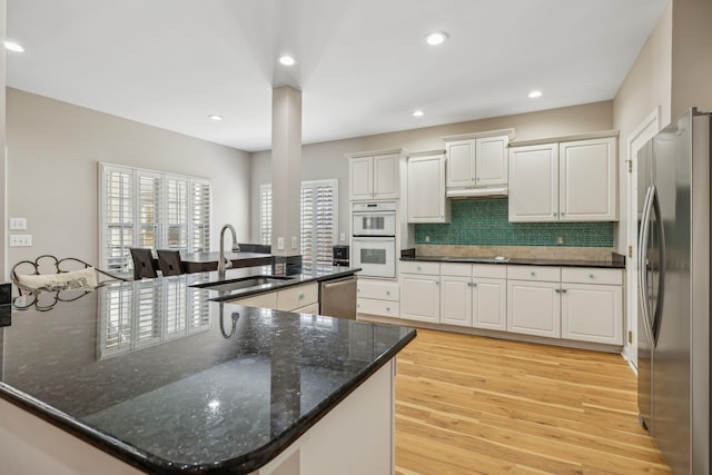 kitchen featuring stainless steel appliances, white cabinetry, sink, and kitchen peninsula