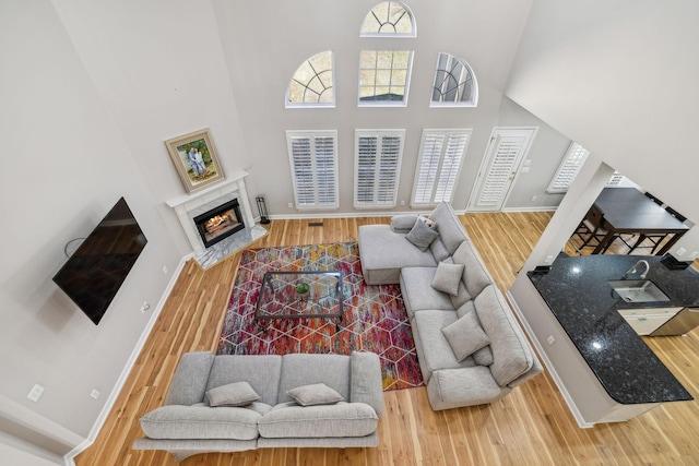 living room with a towering ceiling, a high end fireplace, and wood-type flooring