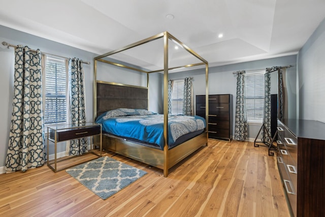 bedroom with hardwood / wood-style floors and a tray ceiling