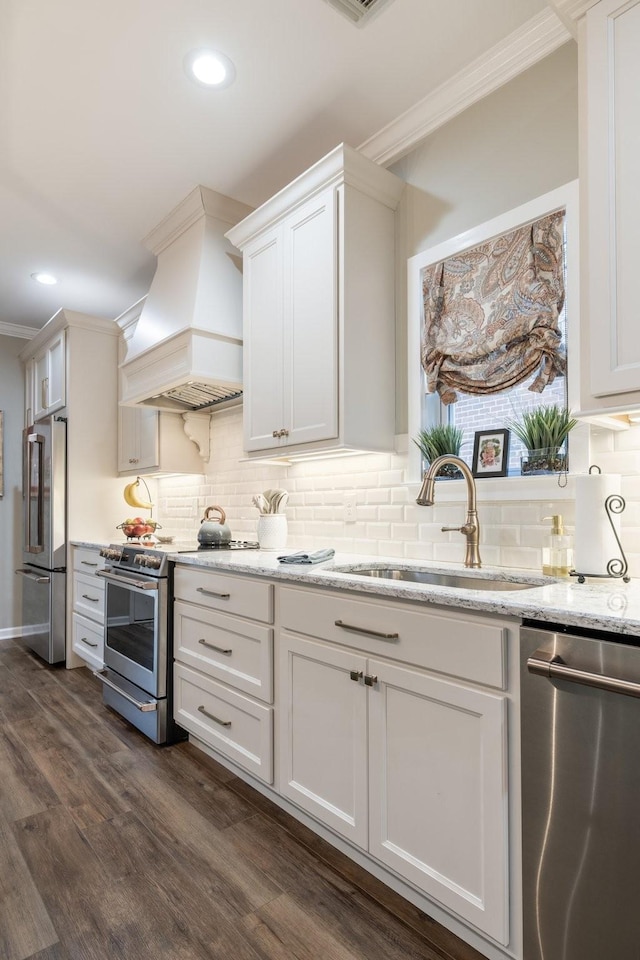 kitchen with sink, custom range hood, white cabinets, and appliances with stainless steel finishes