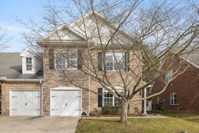 view of front of house with a garage, central AC, and a front lawn