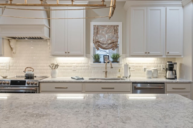 kitchen with sink, white cabinets, decorative backsplash, light stone counters, and stainless steel appliances