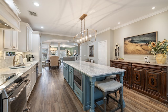 kitchen featuring sink, appliances with stainless steel finishes, a center island, white cabinets, and decorative light fixtures