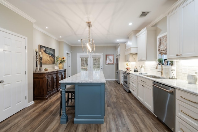 kitchen with decorative light fixtures, white cabinetry, a center island, stainless steel appliances, and custom range hood