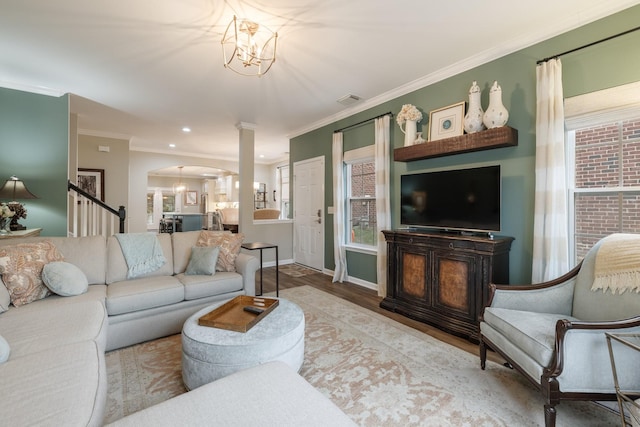 living room with crown molding, ornate columns, light hardwood / wood-style flooring, and a notable chandelier