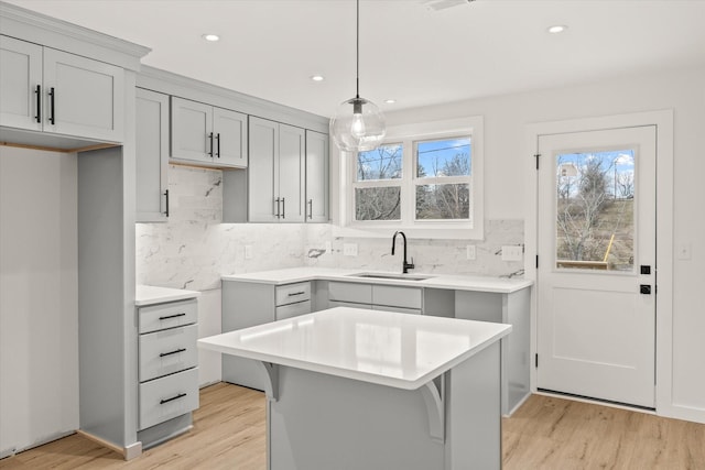 kitchen featuring hanging light fixtures, a center island, sink, and light hardwood / wood-style floors