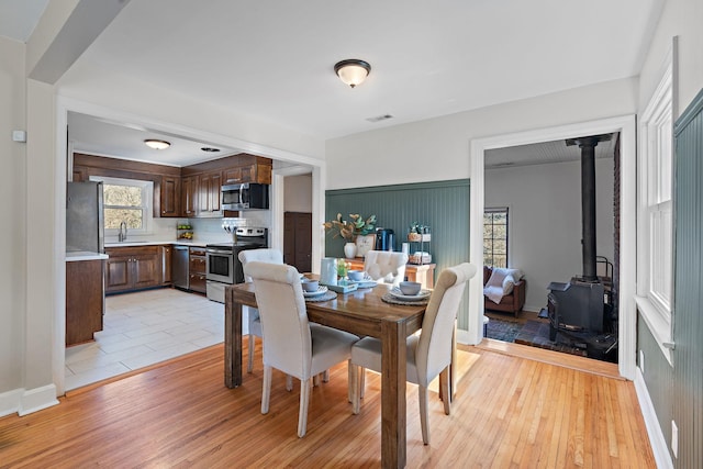 dining room with sink, light wood-type flooring, and a wood stove