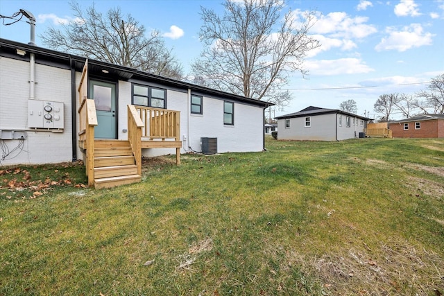 rear view of house with central AC unit and a lawn