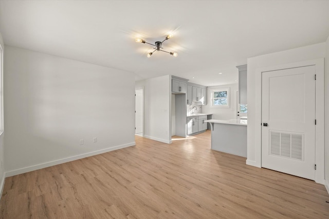 unfurnished living room featuring sink and light hardwood / wood-style floors