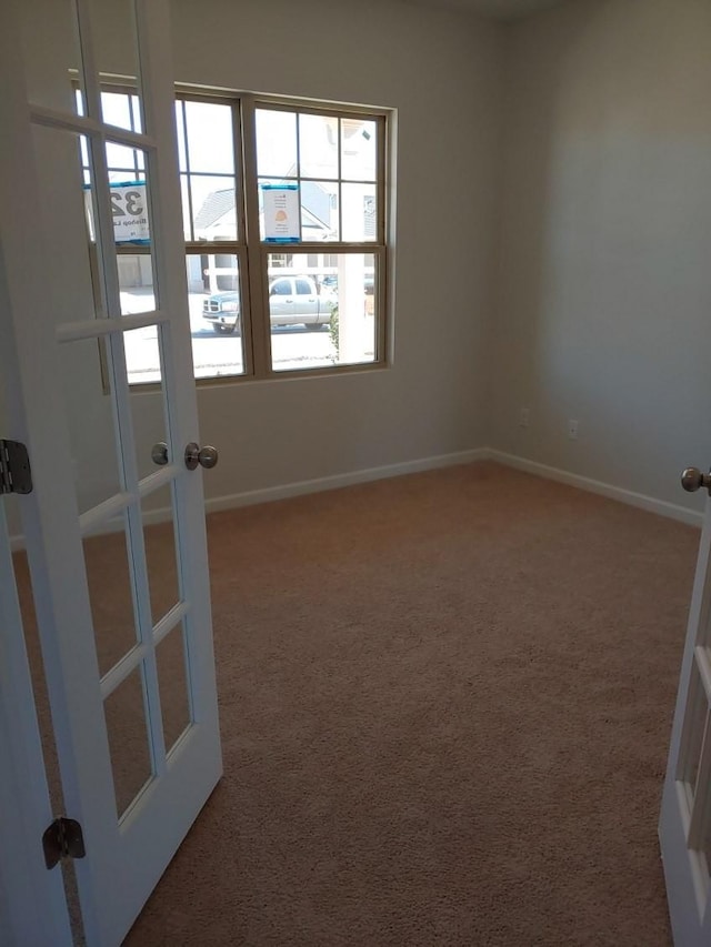 carpeted spare room featuring french doors