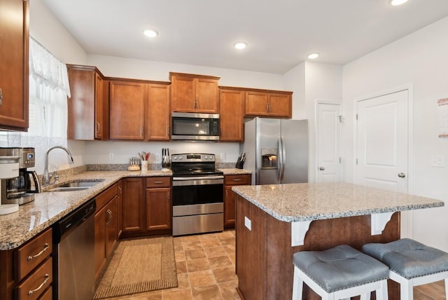 kitchen with light stone countertops, a kitchen breakfast bar, a center island, and appliances with stainless steel finishes