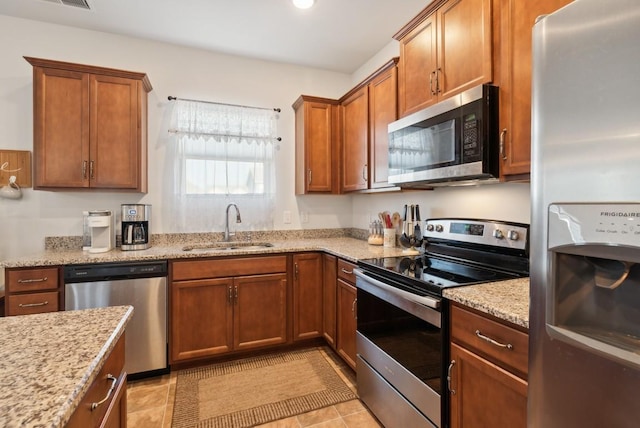 kitchen featuring appliances with stainless steel finishes, light stone countertops, sink, and light tile patterned floors