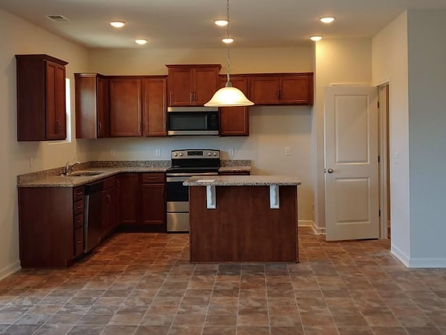 kitchen with pendant lighting, sink, stainless steel appliances, light stone countertops, and a kitchen island