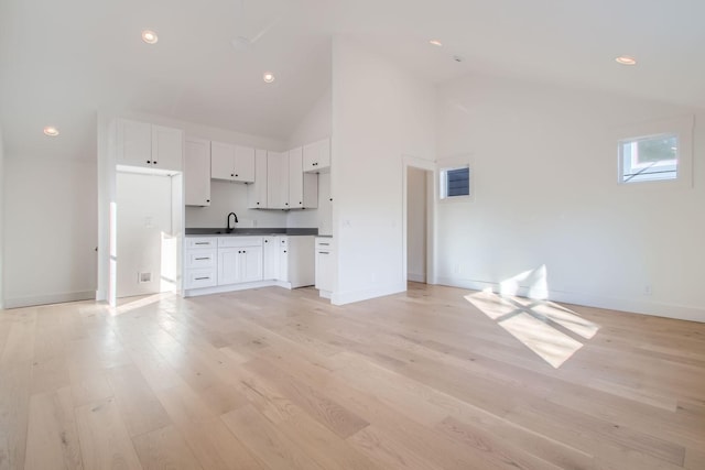 unfurnished living room with high vaulted ceiling, sink, and light hardwood / wood-style floors