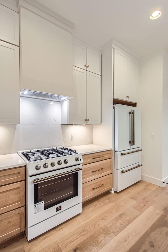 kitchen with tasteful backsplash, white appliances, white cabinets, and light wood-type flooring