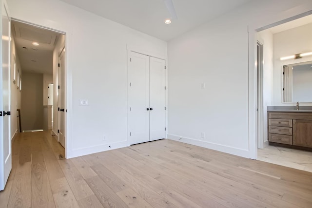 unfurnished bedroom with connected bathroom, sink, light hardwood / wood-style floors, and a closet