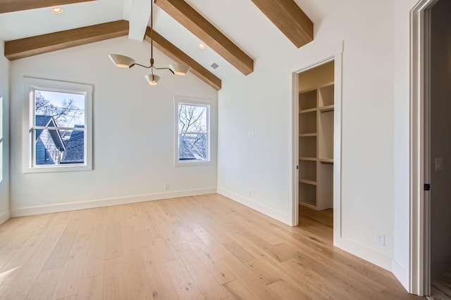 interior space with vaulted ceiling with beams, a spacious closet, a closet, and light wood-type flooring