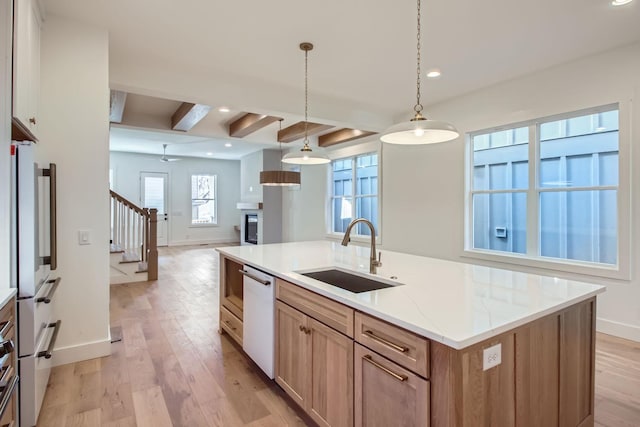 kitchen with sink, dishwasher, hanging light fixtures, fridge, and a center island with sink