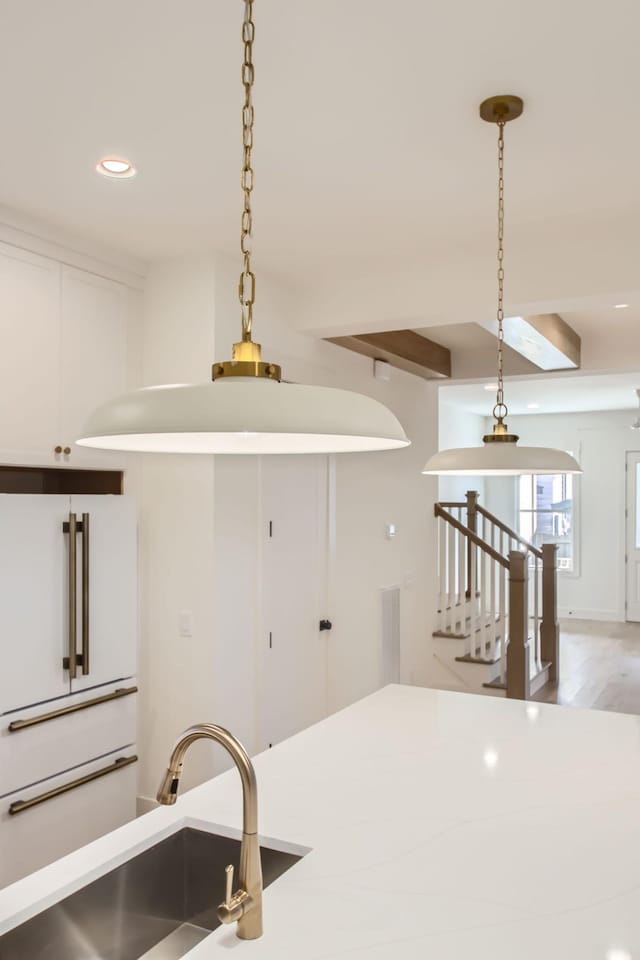 kitchen with pendant lighting, sink, light hardwood / wood-style flooring, beam ceiling, and high end white fridge