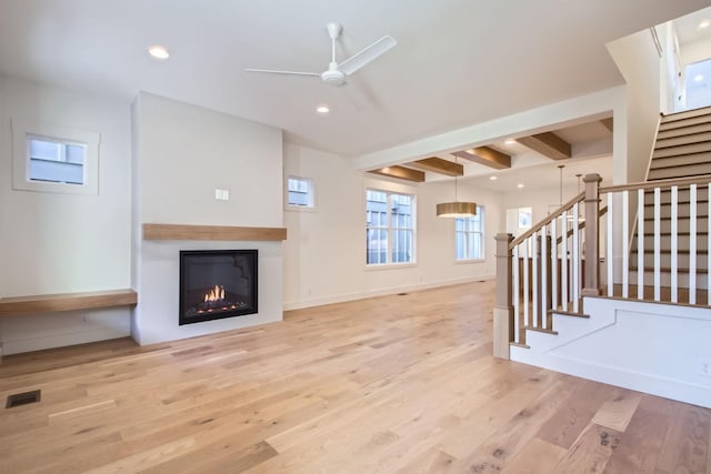 unfurnished living room featuring beam ceiling, light hardwood / wood-style floors, and ceiling fan