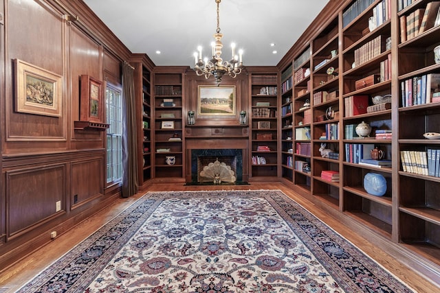 living area featuring hardwood / wood-style flooring, crown molding, a chandelier, and a high end fireplace