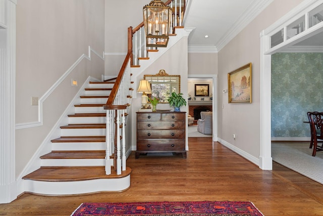 stairway featuring ornamental molding, wood-type flooring, and a brick fireplace