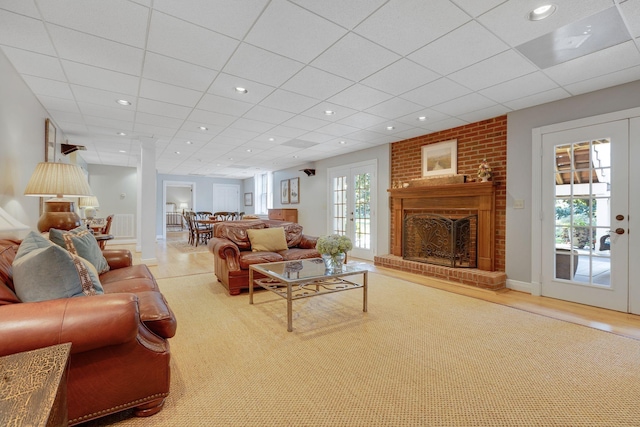 living room with french doors, a healthy amount of sunlight, a fireplace, and a drop ceiling