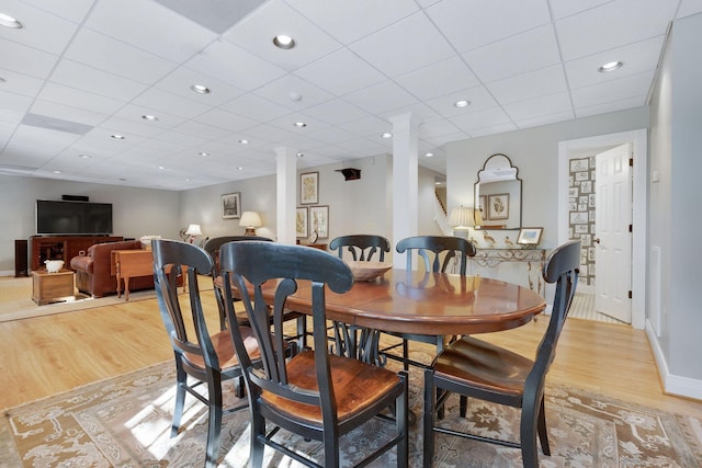 dining area with decorative columns and light wood-type flooring