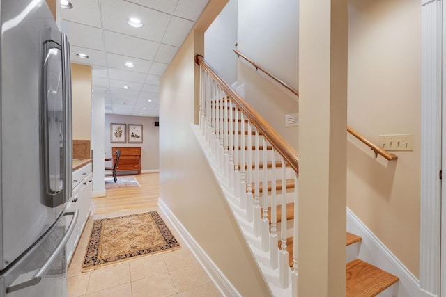 staircase with a drop ceiling and tile patterned floors