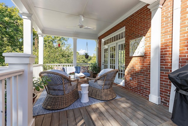 wooden terrace with an outdoor living space, covered porch, and ceiling fan