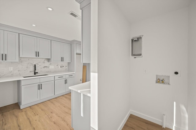 kitchen with tasteful backsplash, sink, and light wood-type flooring