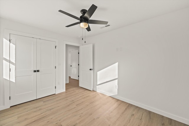 unfurnished bedroom featuring ceiling fan, light hardwood / wood-style floors, and a closet