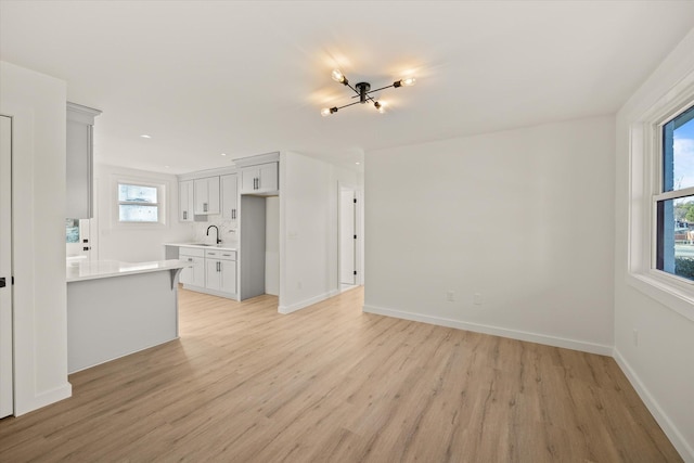 kitchen with white cabinetry, sink, light hardwood / wood-style flooring, and kitchen peninsula