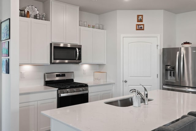 kitchen with stainless steel appliances, light stone countertops, sink, and white cabinets