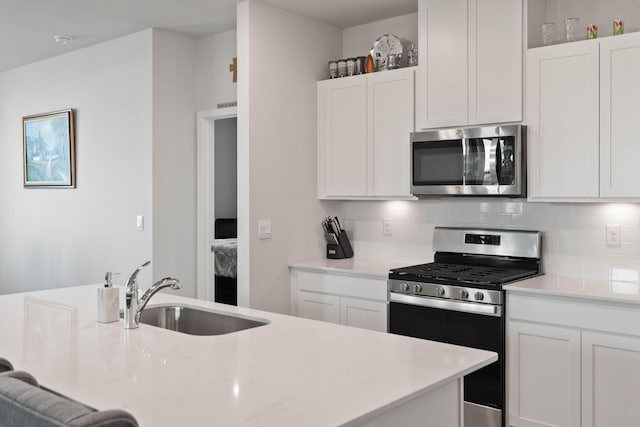 kitchen with sink, backsplash, stainless steel appliances, and white cabinets