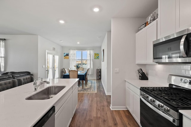 kitchen with sink, white cabinetry, appliances with stainless steel finishes, dark hardwood / wood-style flooring, and decorative backsplash