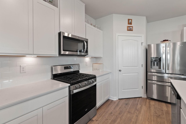 kitchen featuring white cabinetry, backsplash, light hardwood / wood-style flooring, and appliances with stainless steel finishes