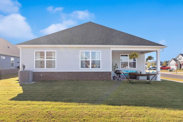 rear view of house with central AC and a lawn