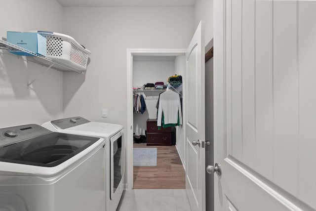 clothes washing area with separate washer and dryer and light wood-type flooring