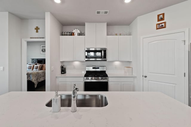 kitchen with stainless steel appliances, sink, white cabinets, and backsplash